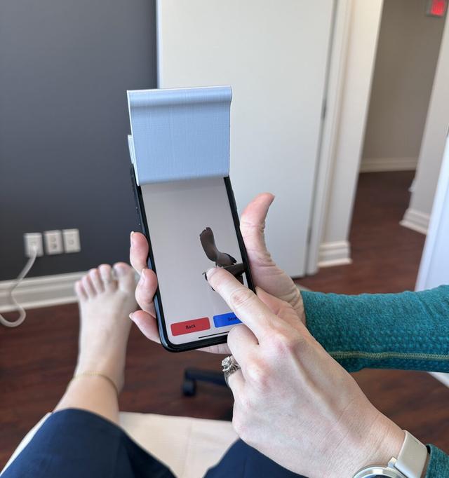A chiropodist reviewing a patient's 3D foot scan on screen