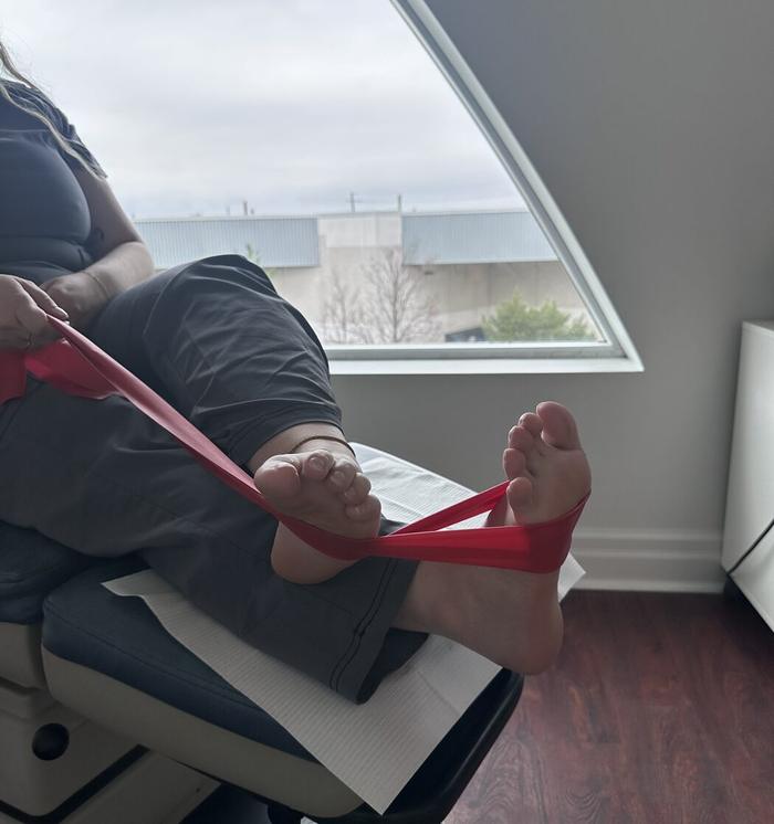 A patient doing an ankle strengthening exercise with a resistance band in the treatment chair