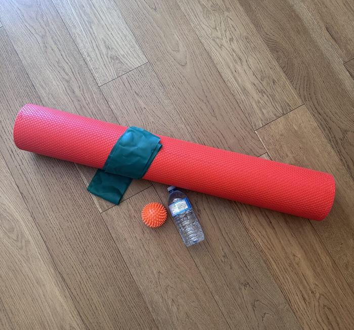 A foam roller, massage ball and water bottle used for home stretching and loading exercises
