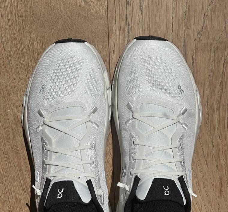 A pair of supportive white running shoes, seen from above