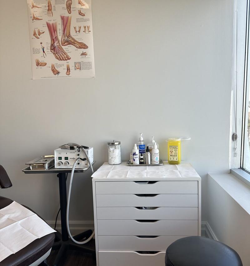 A treatment room with a treatment chair, instrument drawers and a foot anatomy poster