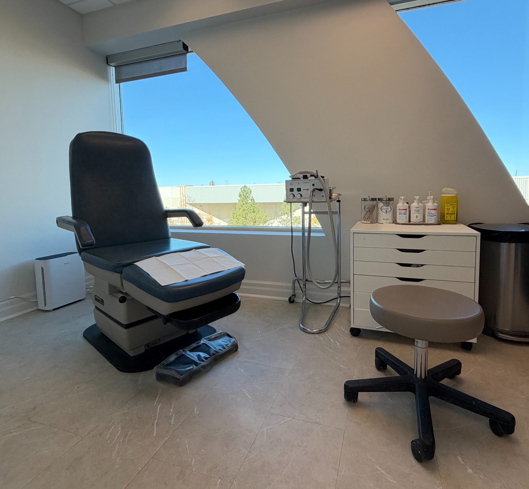 A bright treatment room at Aurora Foot Clinic & Orthotic Centre, with a treatment chair beside a large angled window